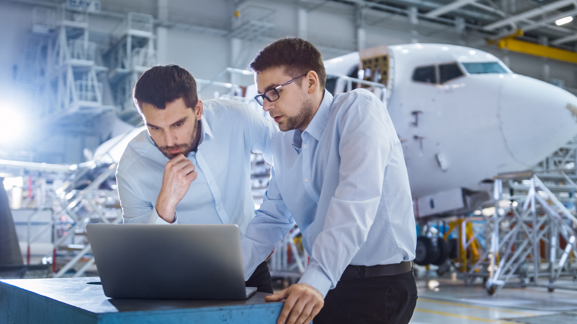 Two aviation professionals reviewing work beside an aircraft