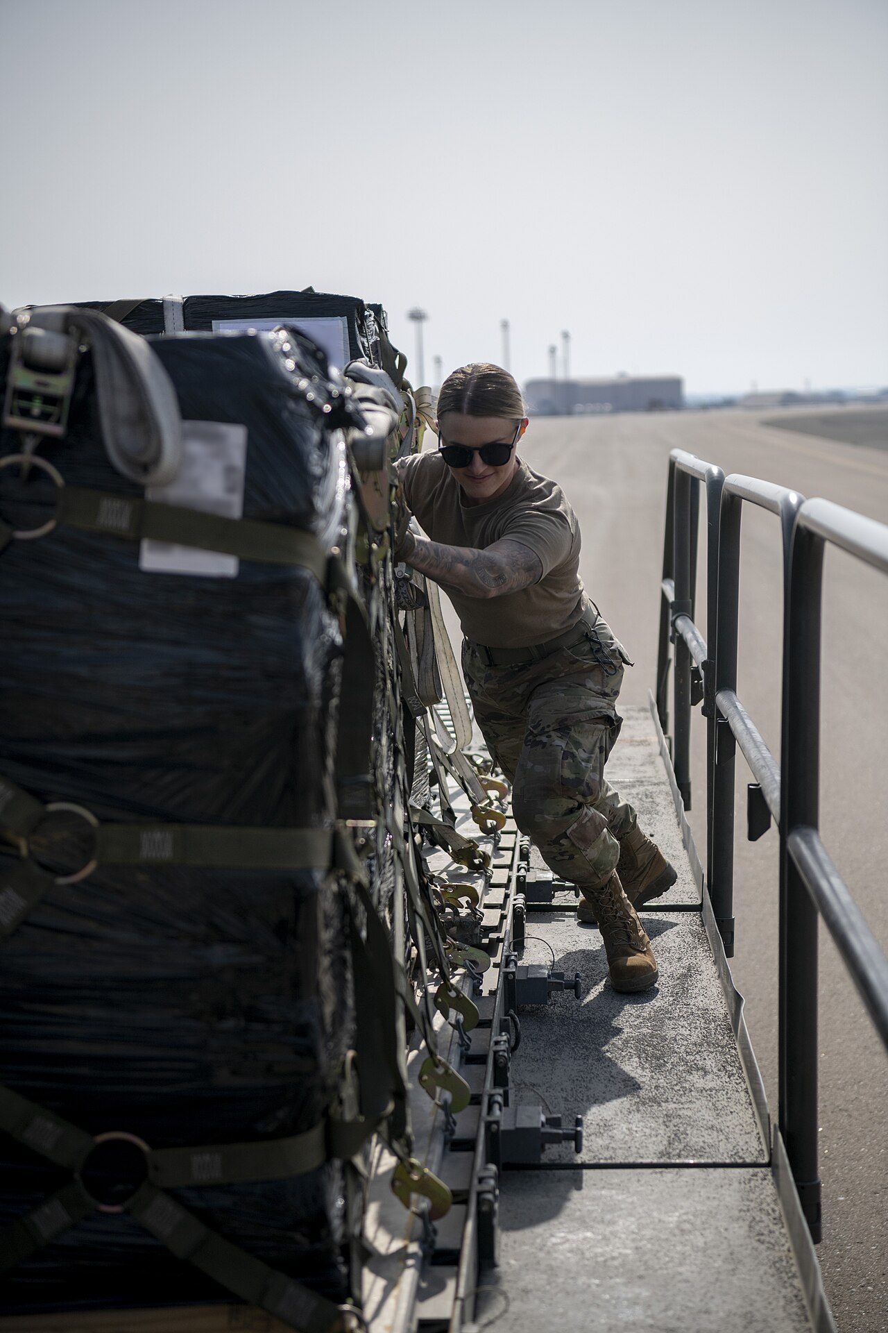 Air force crew member handling cargo equipment beside an aircraft