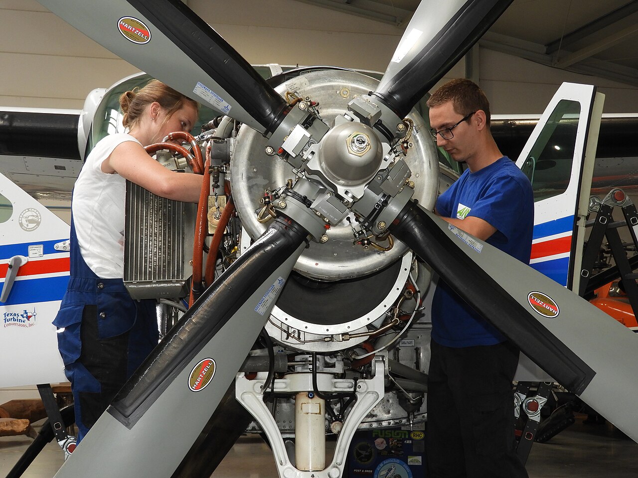 Two technicians servicing an aircraft propeller assembly